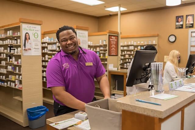 Employee smiling from behind the pharmacy counter